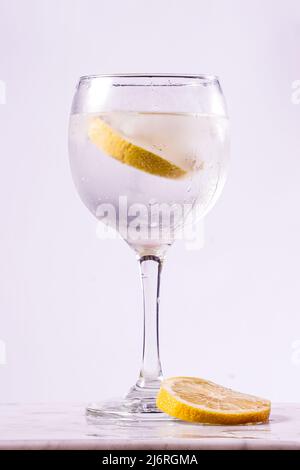 verre tonique de gin avec tranches de citron sur fond blanc Banque D'Images