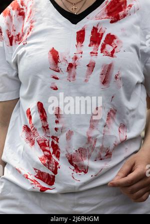 Kiev, Ukraine, 3 mai 2022, T-shirt avec des traces de peinture rouge symbolisant le sang des victimes innocentes de la guerre. Les jeunes militantes se préparent au rassemblement en appliquant de la peinture rouge sur elles-mêmes, symbolisant le sang. Des femmes, des mères, des enfants de soldats ukrainiens et des membres du bataillon Azov à Marioupol se sont réunis sur la place de l'indépendance pour assister à un rassemblement pour appeler les leaders mondiaux à l'action pour aider à organiser un couloir humanitaire pour l'évacuation des civils et des militaires ukrainiens de la ville assiégée de Marioupol vers les pays neutres, Kiev, Ukraine, 3 mai 2022 Banque D'Images