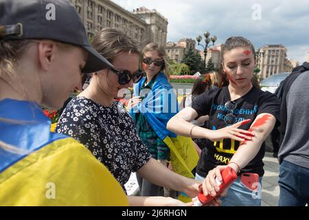 Kiev, Ukraine, 3 mai 2022, de jeunes militantes se préparent au rassemblement en appliquant de la peinture rouge sur elles-mêmes, symbolisant le sang. Des femmes, des mères, des enfants de soldats ukrainiens et des membres du bataillon Azov à Marioupol se sont réunis sur la place de l'indépendance pour assister à un rassemblement pour appeler les leaders mondiaux à l'action pour aider à organiser un couloir humanitaire pour l'évacuation des civils et des militaires ukrainiens de la ville assiégée de Marioupol vers les pays neutres, Kiev, Ukraine, 3 mai 2022 Banque D'Images