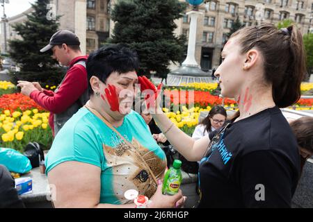 Kiev, Ukraine, 3 mai 2022, de jeunes militantes se préparent au rassemblement en appliquant de la peinture rouge sur elles-mêmes, symbolisant le sang. Des femmes, des mères, des enfants de soldats ukrainiens et des membres du bataillon Azov à Marioupol se sont réunis sur la place de l'indépendance pour assister à un rassemblement pour appeler les leaders mondiaux à l'action pour aider à organiser un couloir humanitaire pour l'évacuation des civils et des militaires ukrainiens de la ville assiégée de Marioupol vers les pays neutres, Kiev, Ukraine, 3 mai 2022 Banque D'Images