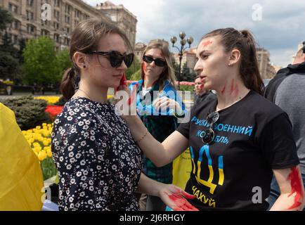 Kiev, Ukraine, 3 mai 2022, de jeunes militantes se préparent au rassemblement en appliquant de la peinture rouge sur elles-mêmes, symbolisant le sang. Des femmes, des mères, des enfants de soldats ukrainiens et des membres du bataillon Azov à Marioupol se sont réunis sur la place de l'indépendance pour assister à un rassemblement pour appeler les leaders mondiaux à l'action pour aider à organiser un couloir humanitaire pour l'évacuation des civils et des militaires ukrainiens de la ville assiégée de Marioupol vers les pays neutres, Kiev, Ukraine, 3 mai 2022 Banque D'Images