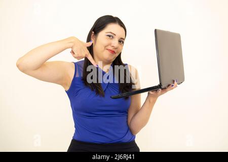 Mignon asiatique et PDG à succès, portant un chemisier bleu heureux de démontrer son travail, tenant l'ordinateur portable avec sa main, sur fond blanc Banque D'Images