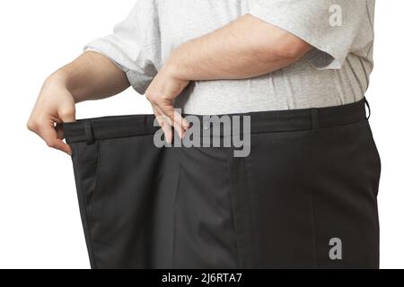 L'homme tire sur son grand pantalon à la taille. Montre comment il a perdu du poids. Banque D'Images