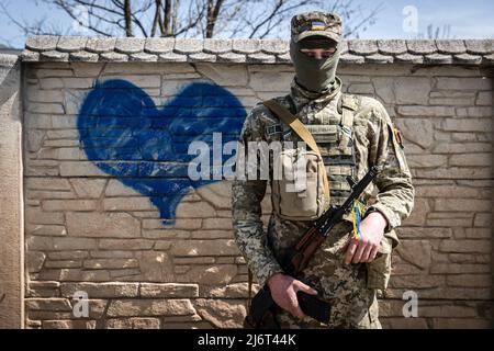 25 avril 2022, Kharkiv, Ukraine : un soldat ukrainien pose une photo devant un mur de graffiti au cours de sa patrouille dans un endroit non divulgué de l'oblast de Kharkiv. Alors que la guerre entre l'Ukraine et la Russie fait rage depuis plus de deux mois, la Russie a maintenant déplacé son objectif tactique vers la partie orientale de l'Ukraine et a maintenant concentré l'offensive sur la partie orientale du pays. L’oblast de Kharkiv fait désormais l’objet d’une menace constante de bombardements et de frappes aériennes russes. La Russie a envahi l'Ukraine le 24 février 2022, déclenchant la plus grande attaque militaire en Europe depuis la Seconde Guerre mondiale (Image de crédit : © Alex Chan TSZ Yuk Banque D'Images