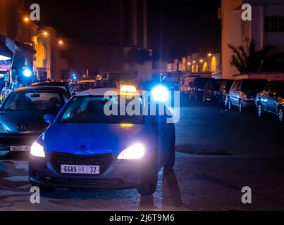 Taxi bleu nuit passant dans les rues d'Essaouira, Maroc Banque D'Images