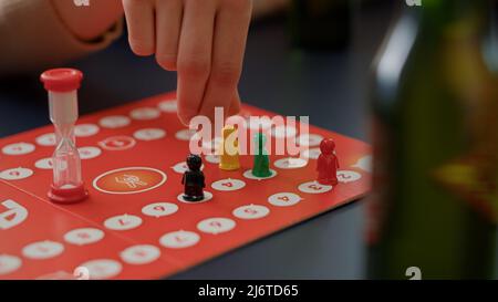 Les jeunes jouent à des jeux de société de charades avec des figurines, des dés roulants pour des jeux de cartes. Les hommes et les femmes qui apprécient la stratégie de compétition pour deviner carte pour le divertissement et le plaisir. Gros plan. Banque D'Images