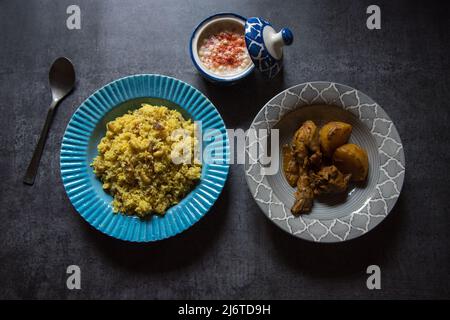 Repas indien à base de riz basmati et de curry de poulet servi dans un bol sur fond sombre. Vue de dessus, mise au point sélective. Banque D'Images