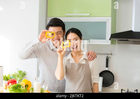 Dans la cuisine familiale, un jeune couple qui apprécie la cuisine ensemble en prenant des tranches de poivron jaune - photo de stock Banque D'Images
