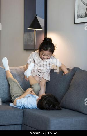 Une petite fille et un petit garçon jouant sur le canapé - photo de stock Banque D'Images