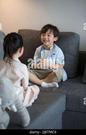 Une petite fille et un petit garçon jouent main clapping sur le canapé du salon - photo de stock Banque D'Images