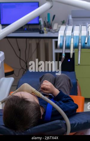 enfant avec sédation en chaise dentaire. réception d'un dentiste pédiatrique, traitement dentaire sous sédation Banque D'Images