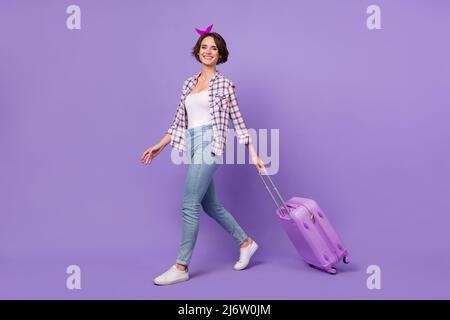 Profil complet photo de côté de jeune jolie fille marche enregistrement vol voyage à l'étranger isolé sur fond violet couleur Banque D'Images
