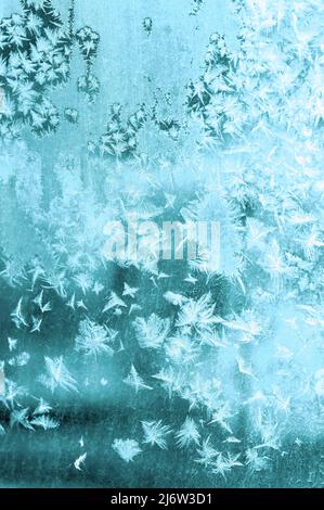 Motif givré de flocons de neige ajourés sur la fenêtre en gros plan. Turquoise Banque D'Images