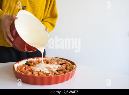 Femme verse une quiche avec un mélange d'œufs et de crème. Quiche au saumon. Cuisson. Banque D'Images