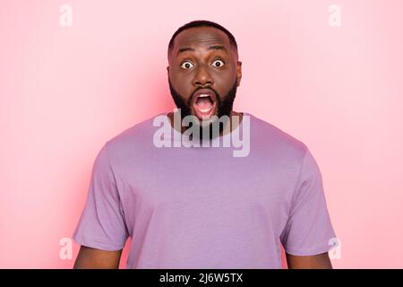 Photo de choqué funky Guy habillé violet t-shirt ouvert bouche grands yeux isolé couleur rose fond Banque D'Images