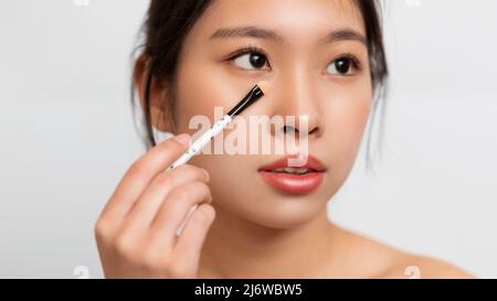 Portrait d'une femme asiatique avec pinceau à maquillage Banque D'Images
