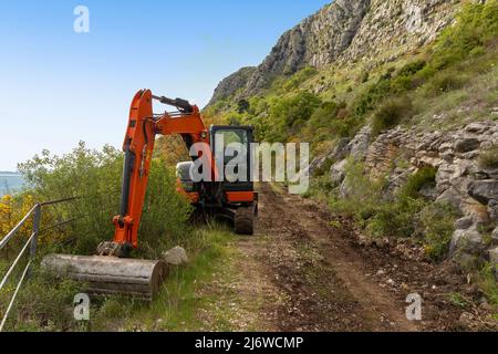 Pelle hydraulique sur la route du turist basée dans la région de Konavle près de Dubrovnik. La route le long de la pente de la montagne au-dessus de la vallée. Banque D'Images