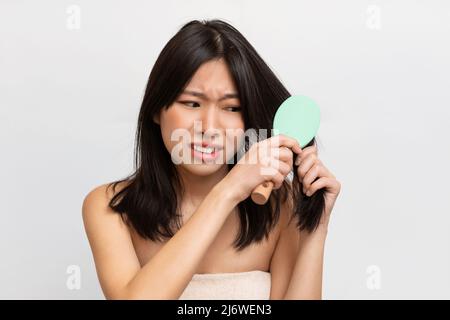 Portrait d'une femme asiatique malheureuse se brossant les cheveux Banque D'Images