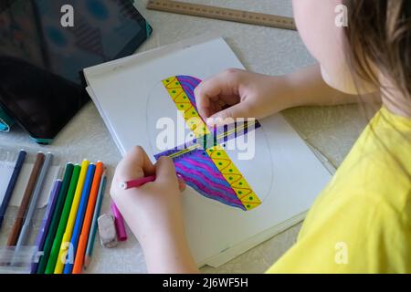 La fille dessine une photo dans l'album avec des stylos feutre. Stylos-feutres et tablette sur la table près de l'enfant Banque D'Images