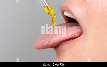 pipette à huile de langue. herbes médecine alternative et compléments alimentaires femme prenant cbd huile de chanvre gouttes dans la bouche de dropper. S Banque D'Images