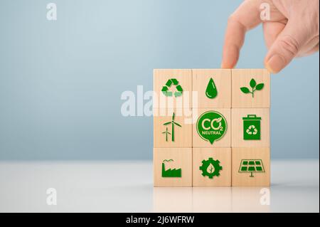 Stratégie à long terme neutre en matière de climat. Mettez à la main des cubes en bois avec une icône verte et une icône verte sur fond bleu. Stratégie à long terme neutre en matière de climat. Woode Banque D'Images