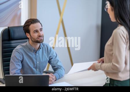 Le PDG souriant communique avec la femme secrétaire de son bureau Banque D'Images