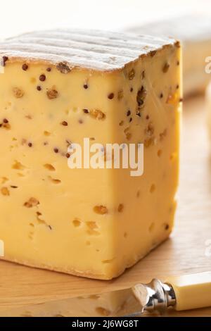 Morceau de fromage belge aux graines de moutarde et Fenugrec sur une planche à découper Banque D'Images