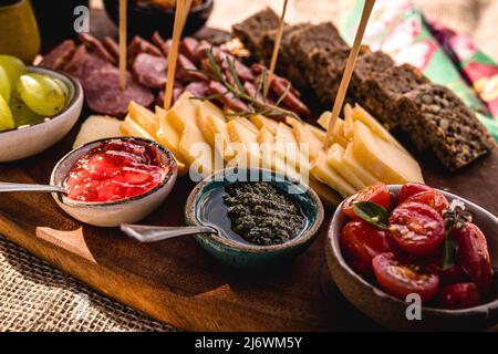 Viandes froides, en-cas et garnitures, avec parmesan artisanal, tomates fraîches, pain noir allemand, confiture, sauce pesto, concombres, raisins verts et légumes Banque D'Images