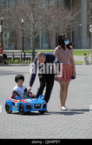 Un jour de printemps doux, une famille prend son fils pour faire un tour dans sa voiture électrique. Dans un parc à Queens, New York. Banque D'Images