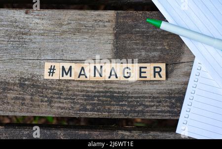 Des blocs de jouets en bois avec le gestionnaire de texte dessus avec le stylo et le papier en arrière-plan. Photo parfaite pour les recruteurs, les RH, les entreprises, les entreprises Banque D'Images