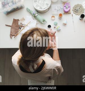 Processus de fabrication du jouet, vue du dessus. Femme en train de fabriquer un jouet en peluche fait main, atelier à la maison Banque D'Images