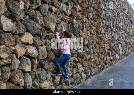 Une petite fille parle des trains sur le mur d'escalade dans le parc de la ville d'été. Banque D'Images