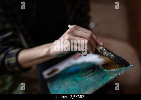 Gros plan sur les mains de l'artiste femme inconnue femme caucasienne ou fille peinture sur toile en utilisant le pinceau et les couleurs pour faire de l'art professionnel ou hobby Banque D'Images