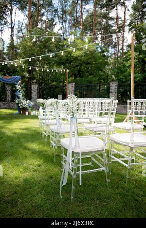 Chaises fleuries pour les invités lors d'une cérémonie de mariage en plein air. Mise au point sélective douce. Banque D'Images