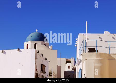 Oia, Santorini, Iles grecques, Grèce - rue principale bordée de boutiques et église avec dôme bleu à distance Banque D'Images