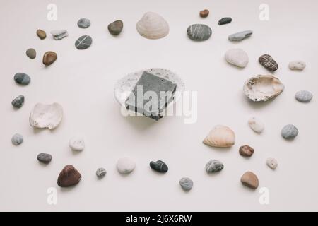 Savon biologique naturel sur un porte-savon en céramique avec coquillages et pierres sur fond blanc. Concept spa. Flat lay, vue de dessus Banque D'Images