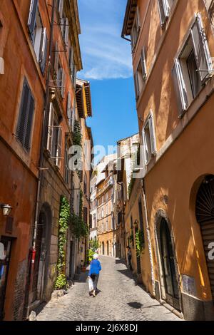 Femme de haut niveau qui marche dans une rue étroite de la ville de Rome en Italie. Banque D'Images