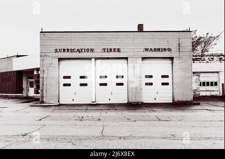 Atelier de réparation automobile de conception classique, maintenant démoli, avec une signalisation au-dessus des portes de garage, « lubrification », « pneus », « lavage » à Ludington, Michigan. Banque D'Images