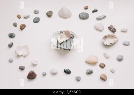 Savon biologique naturel sur un porte-savon en céramique avec coquillages et pierres sur fond blanc. Concept spa. Flat lay, vue de dessus Banque D'Images