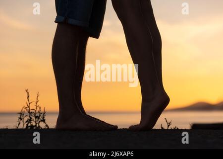 Silhouette d'un couple embrassant. Gros plan sur les jambes. Coucher de soleil en arrière-plan. Concept de la Saint-Valentin. Banque D'Images