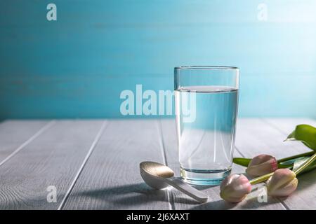 poudre de collagène matcha dans une cuillère et un verre d'eau Banque D'Images