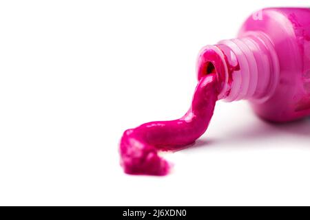 Gros plan d'un tube ouvert de peinture d'artiste magenta qui déborde sur un fond blanc. Banque D'Images