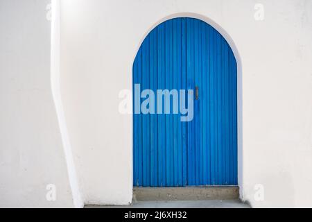 Porte en bois bleu sur fond de mur blanc. Vue sur l'île grecque. Architecture traditionnelle Banque D'Images