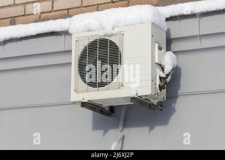 Climatiseur recouvert de neige sur le mur de la maison. Givrage de l'équipement. Banque D'Images