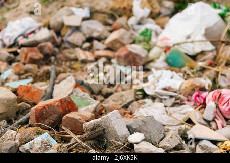 Recentrer d'énormes ruines, épave en Ukraine, la guerre. Maison après attaque russe. Grande pile de déchets sur fond d'herbe verte nature, réchauffement de la planète. Pollution. Banque D'Images