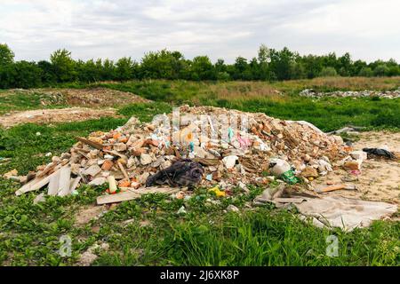 Recentrer d'énormes ruines, épave en Ukraine, la guerre. Maison après attaque russe. Grande pile de déchets sur fond d'herbe verte nature, réchauffement de la planète. Pollution. Banque D'Images