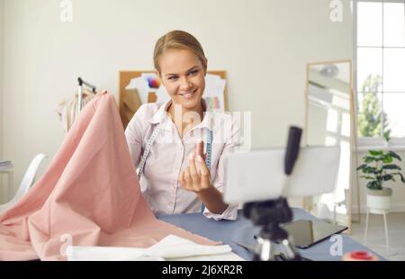 Femme couturière dans son atelier enregistre des cours de couture en ligne ou des vidéos pour le blog. Banque D'Images