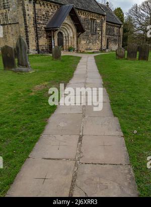 Le chemin menant à l'église paroissiale d'Adel à Leeds. Les dalles de béton ont des croisements indentés. Le chemin traverse le cimetière. Banque D'Images