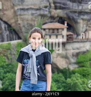 Meteora, Grèce - 29 mai 2021 : une jeune touriste est photographiée sur fond de monastère dans les montagnes. Sommet de la vallée de Meteora. Banque D'Images