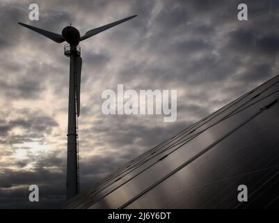 Une petite éolienne sous vent (Endurance E-4660 85kW) et une section d'un petit réseau solaire PV monté au sol à Cornwall, au Royaume-Uni, contre un ciel nocturne. Banque D'Images